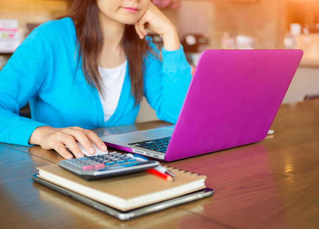 Pretty Young woman using laptop computer. Female working on laptop in an indoor cafe.